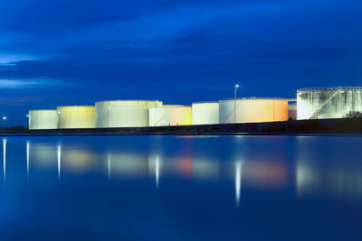 Illuminated factory against blue sky