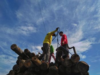 Low angle view of people standing by stack against sky