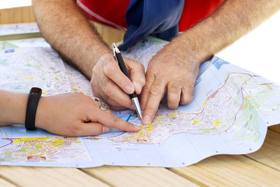 Cropped image of friends pointing on map at table