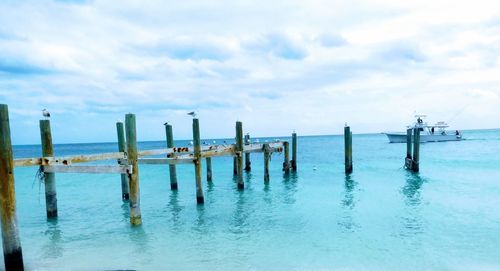Wooden posts in sea against sky