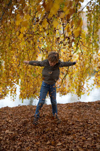 Full length of boy playing with autumn leaves at park