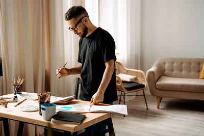 Artist man drawing watercolor. standing and holding paintbrush. looking for inspiration. lifestyle