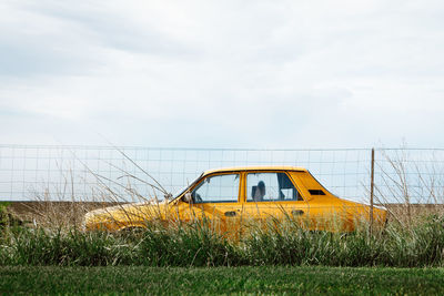 Car parked on field against sky