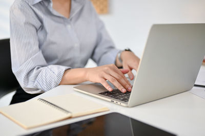 Midsection of businesswoman using laptop at office