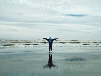 Woman standing at beach against sky