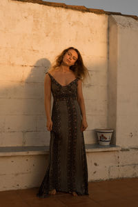 Portrait of a smiling young woman standing against wall