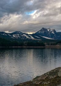 Scenic view of lake by snowcapped mountains against sky