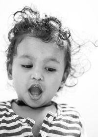 Close-up of girl with mouth open looking down against white background