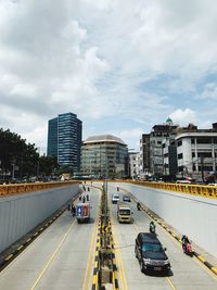 Vehicles on road amidst buildings in city against sky