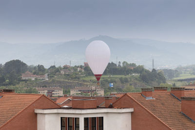Hot air balloon in city against sky