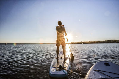 Man standing on boat in sea against clear sky