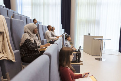 Male and female students studying while sitting in auditorium at university