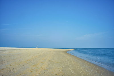 Scenic view of beach against clear blue sky