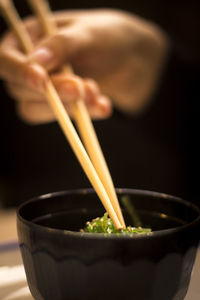 Cropped hand having food in bowl at table