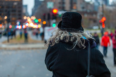 Rear view of woman walking on street in city during winter