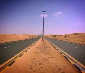 Road amidst desert against sky