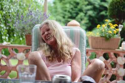 Cheerful mature woman sitting on chair at yard