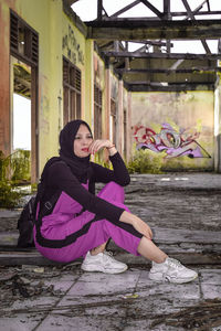 Full length portrait of woman sitting outdoors