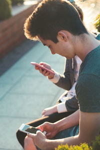 Side view of young man using mobile phone