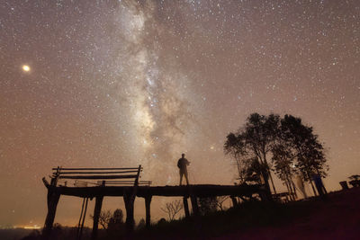 Rear view of man standing on field at night