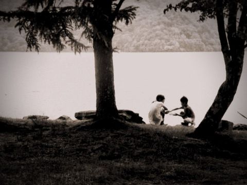 TWO PEOPLE SITTING ON GRASSY FIELD