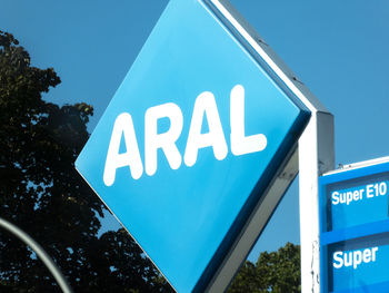 Low angle view of sign against blue sky