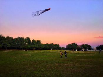 Man with umbrella against sky during sunset