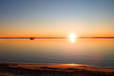 Smooth lake level at warm colorful sunset, sandy beach in bay