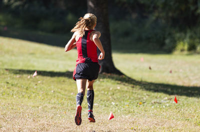 Rear view of woman running on field