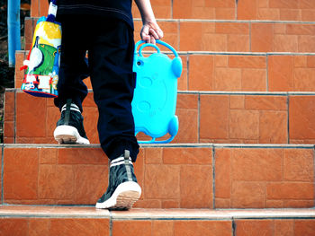 Low section of person holding equipment while moving up on staircase