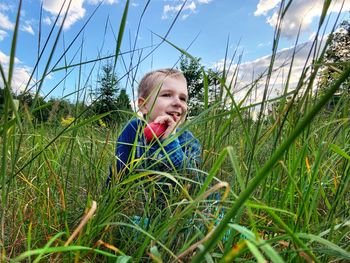 Cute boy looking away while sitting on grassy land