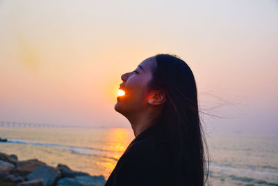 Portrait of woman on beach against sky during sunset