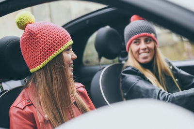 Girls sitting in the car smiling teen in front of the steering wheel with friend enjoying free time 