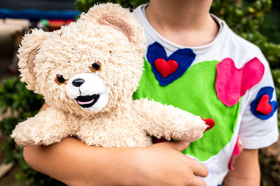 Midsection of child holding toy while standing outdoors