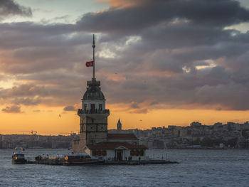 Buildings by sea against sky during sunset