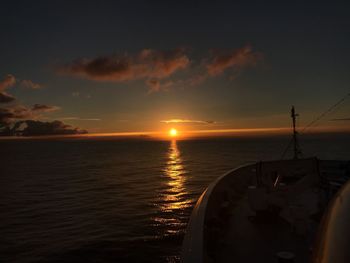 Sailboats moored on sea against sky during sunset