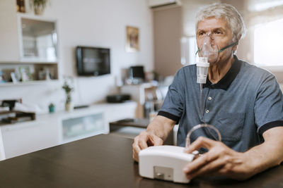 Senior man using inhaler at home
