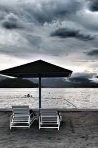 Deck chairs on beach against sky