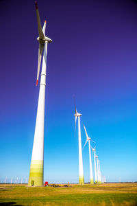 Low angle view of windmill on field against clear blue sky