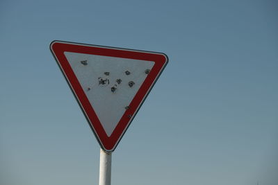 Low angle view of road sign against clear sky