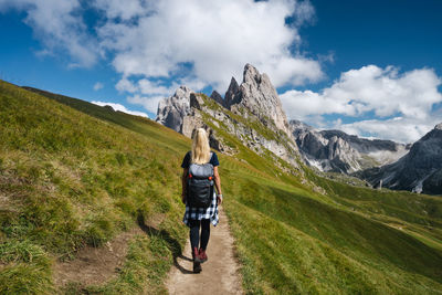 Rear view of woman walking on mountain against sky