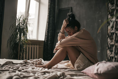 Woman sitting on bed at home