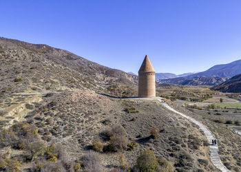 Castle on mountain against clear blue sky