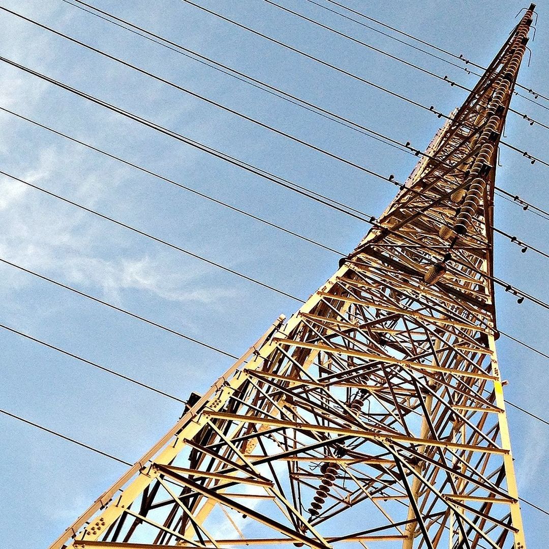 low angle view, built structure, architecture, sky, connection, metal, tall - high, engineering, tower, outdoors, no people, blue, day, metallic, building exterior, part of, cable, electricity pylon, grid, power line