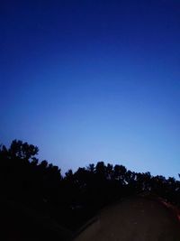 Scenic view of silhouette trees against clear blue sky