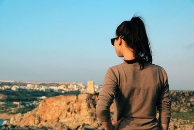 Rear view of young woman standing against clear sky