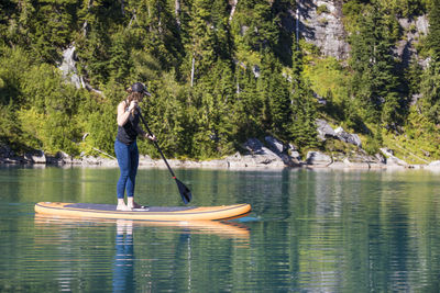 Young woman paddle boarding on remote lake.