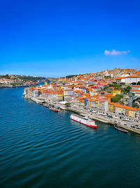 High angle view of townscape by sea against blue sky