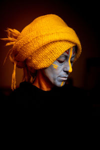 Close-up of man wearing hat against black background