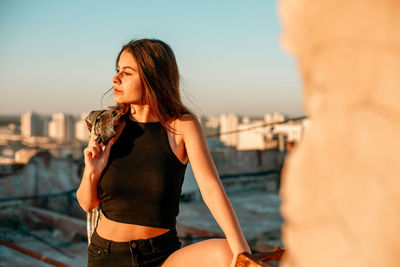 Young woman standing against sky in city